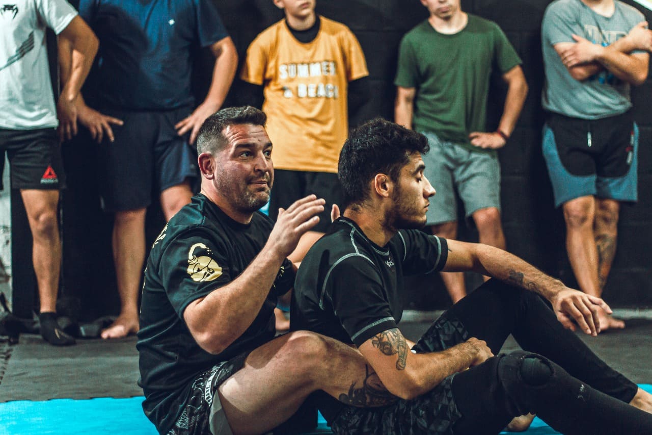 profe de grappling enseñando a tecnica a un alumno