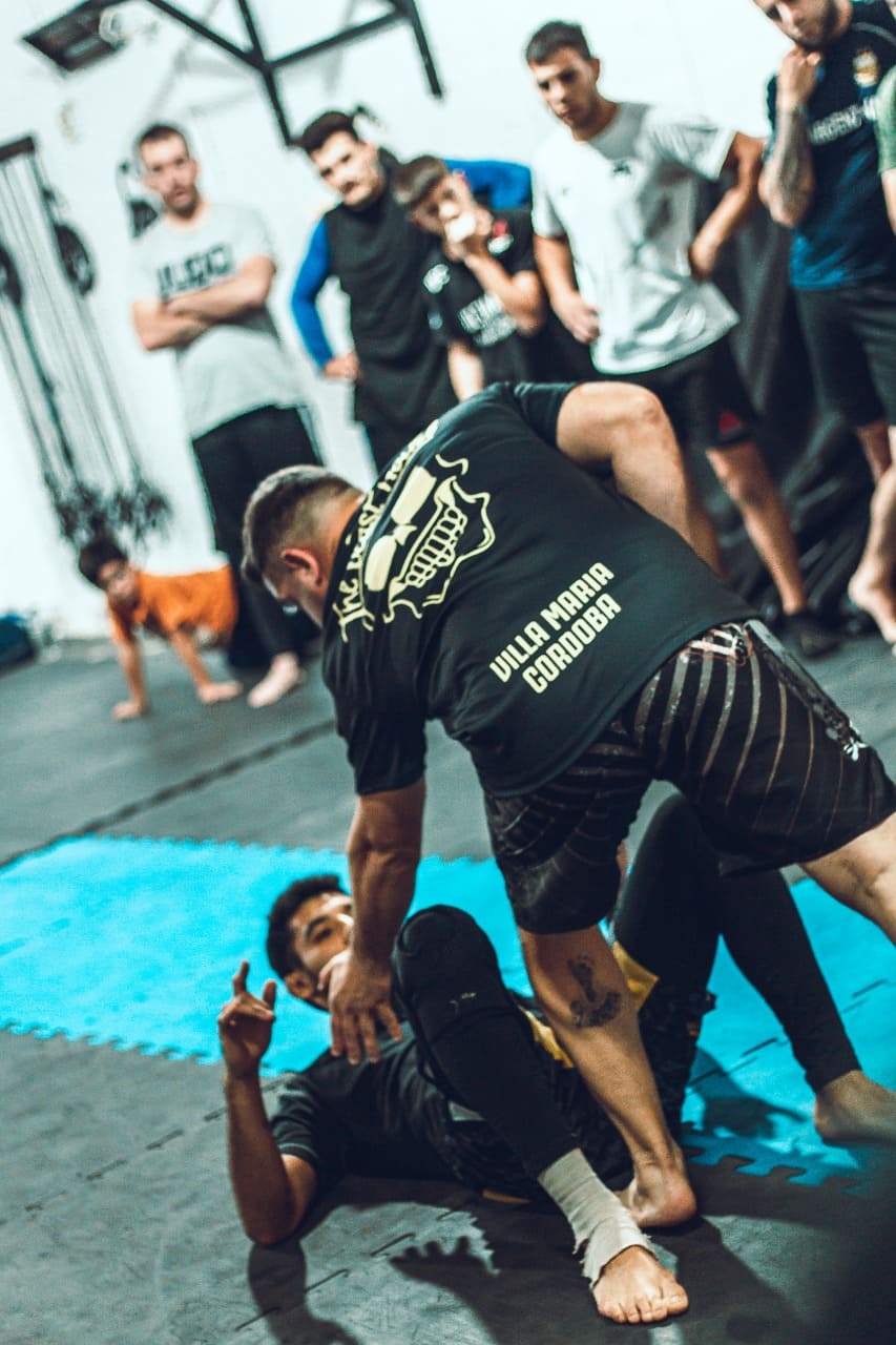 profe de grappling enseñando a tecnica a un alumno